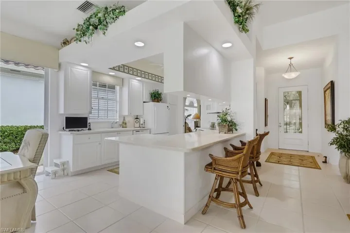 Kitchen with white cabinetry, a peninsula, light tile patterned floors, and freestanding refrigerator