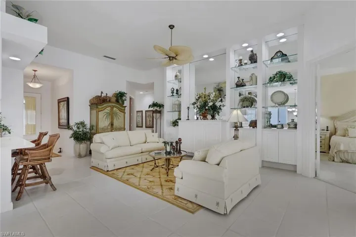 Living room with built in shelves, a ceiling fan, and light tile patterned flooring
