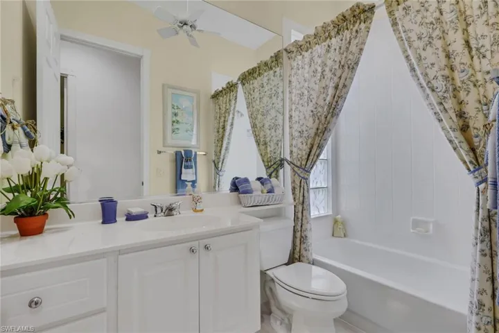 Bathroom with vanity, shower / bath combo, and ceiling fan