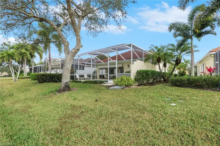 Back of property with glass enclosure, a lawn, stucco siding, and a sunroom