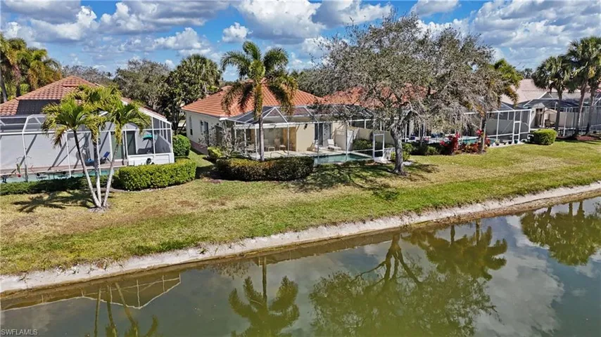 Back of house with a sunroom, a water view, a yard, and a tile roof
