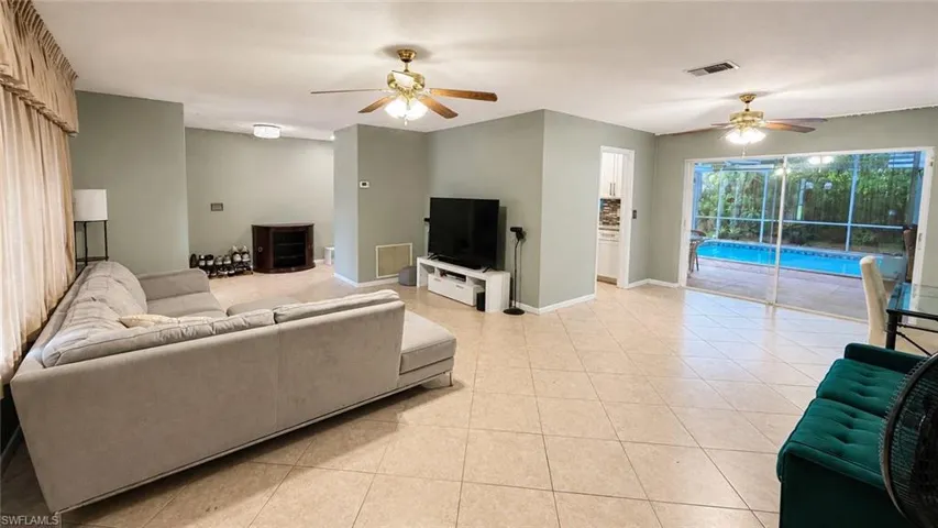 Expansive interior living area featuring neutral wall tones, tile flooring, and two ceiling fans