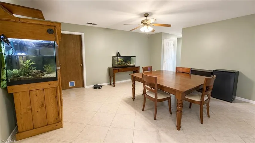 Spacious room featuring light-toned tile flooring, neutral wall paint, and a ceiling fan with integrated lighting