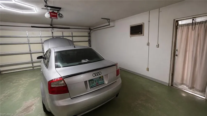 Attached garage featuring an automatic overhead door opener, concrete flooring, a side entry door, and wall-mounted electrical outlets