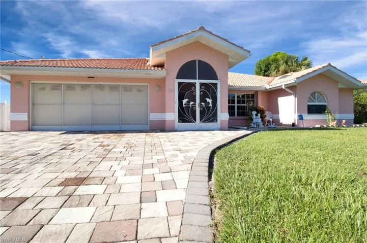 View of front facade with driveway, an attached garage, stucco siding, a front lawn, and a tile roof