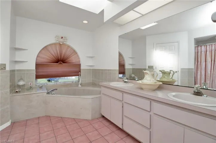 Bathroom with tile patterned flooring, a garden tub, double vanity, and a sink
