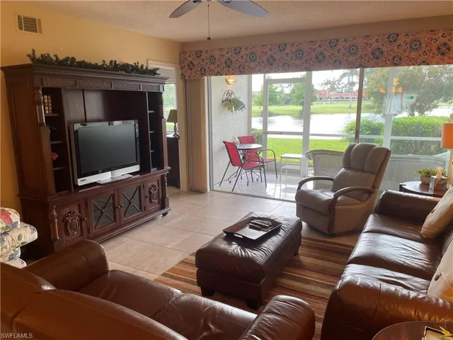 Living room with ceiling fan, light tile patterned flooring, and a textured ceiling
