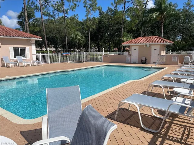 Community pool featuring a patio and view of wooded area