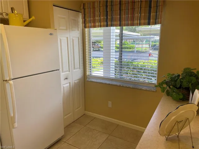 Kitchen featuring freestanding refrigerator, light tile patterned floors, and light countertops