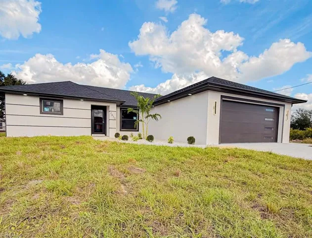 View of front of house with a front lawn, a garage, stucco siding, and concrete driveway