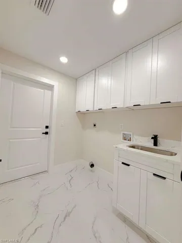 Laundry room with light marble finish flooring, recessed lighting, hookup for a washing machine, hookup for an electric dryer, and cabinet space
