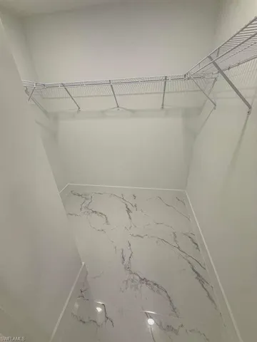 Walk in closet featuring light marble finish floors