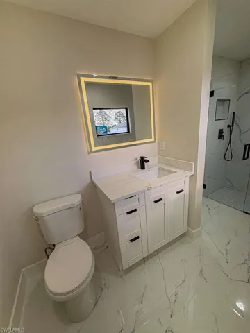 Full bathroom with vanity, light marble finish flooring, and a marble finish shower