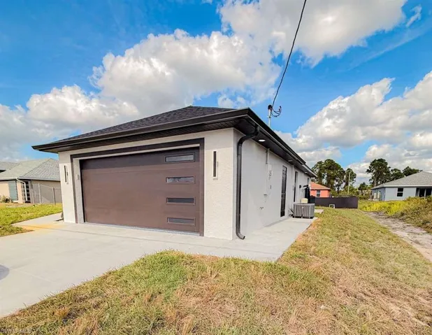 View of side of home featuring stucco siding, a yard, concrete driveway, and an attached garage