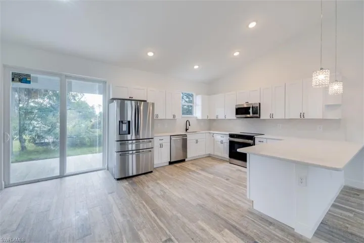 Kitchen featuring white cabinetry, backsplash, kitchen peninsula, pendant lighting, and appliances with stainless steel finishes
