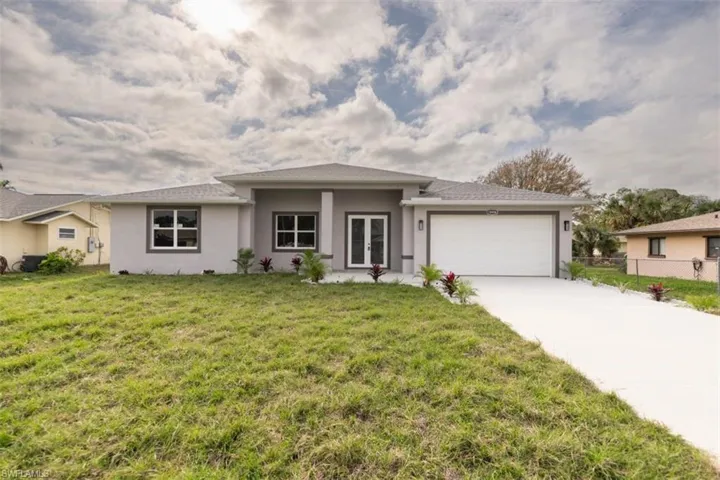 View of front of home with french doors, a garage, and a front lawn