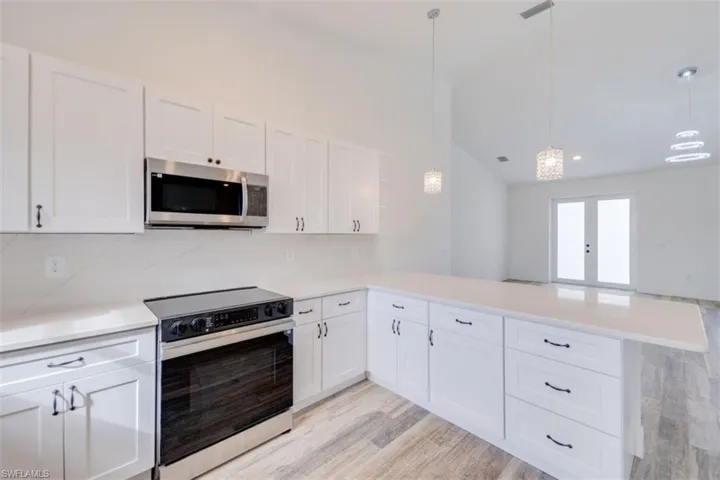 Kitchen featuring kitchen peninsula, pendant lighting, backsplash, and stainless steel appliances