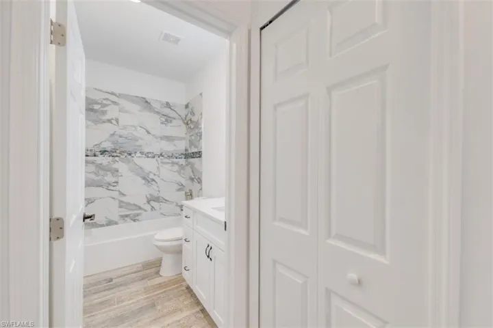 Full bathroom with hardwood / wood-style flooring, vanity, toilet, and tiled shower / bath combo