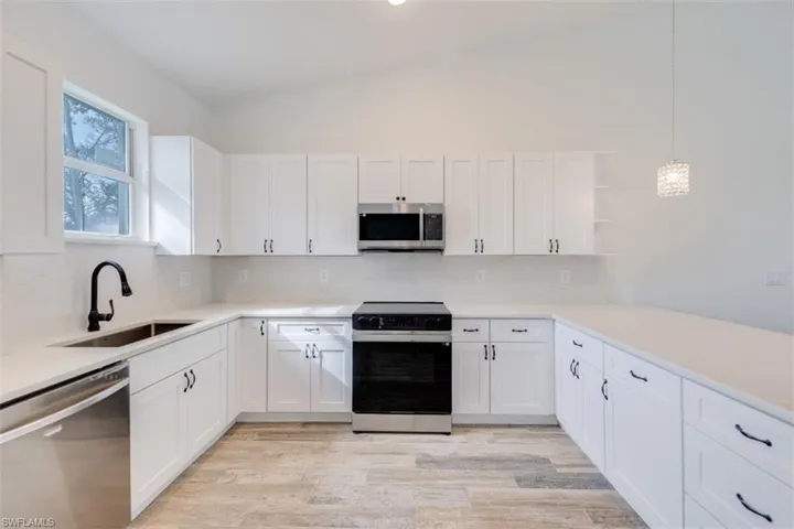 Kitchen with tasteful backsplash, pendant lighting, white cabinets, and stainless steel appliances