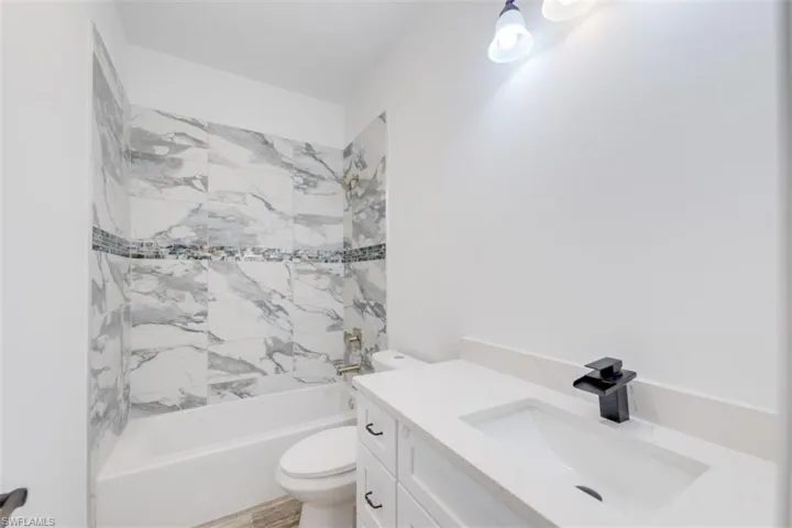 Full bathroom with tiled shower / bath, vanity, and toilet