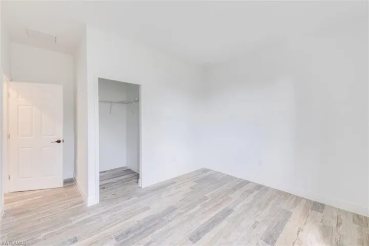 Unfurnished bedroom with a walk in closet, a closet, and light hardwood / wood-style floors