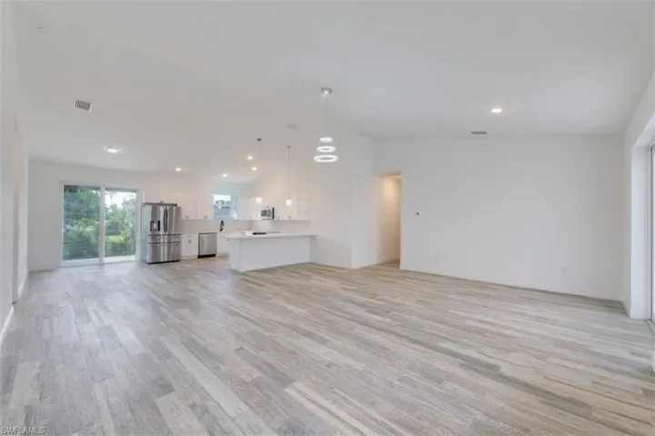 Unfurnished living room with light hardwood / wood-style floors and high vaulted ceiling