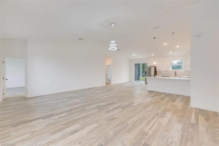 Unfurnished living room with lofted ceiling, sink, and light hardwood / wood-style flooring
