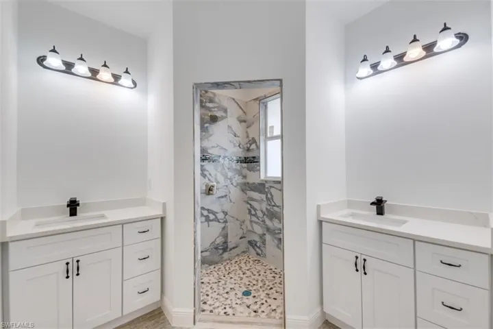 Bathroom featuring tiled shower and vanity