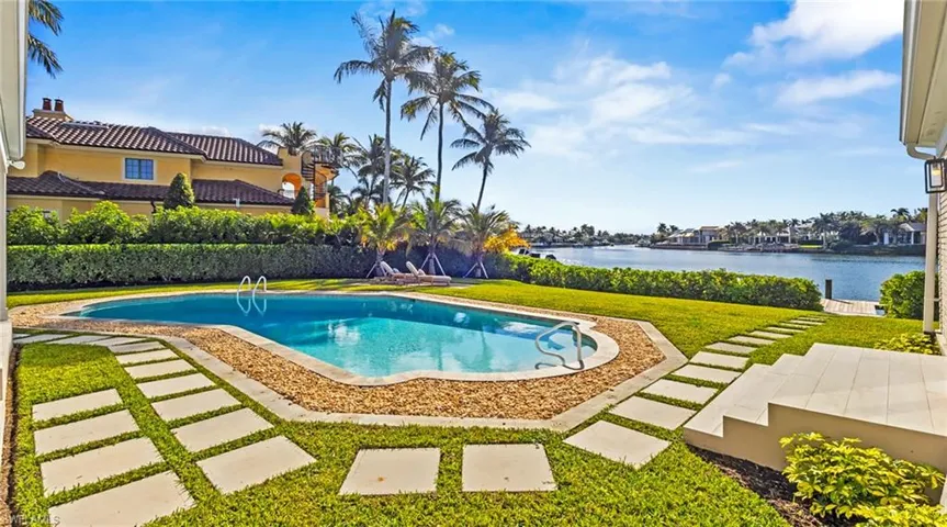 View of swimming pool featuring a yard, patio surround, and a water view