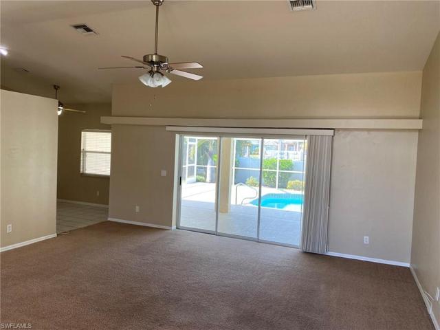 The spacious Living room opens through triple pocket sliding glass doors to the Lanai and Pool.