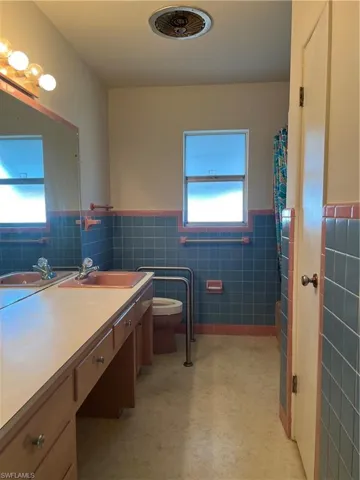 Bathroom with vanity, toilet, curtained shower, and tile walls
