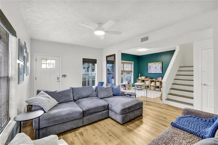 Living area with ceiling fan, light wood finished floors, and a textured ceiling