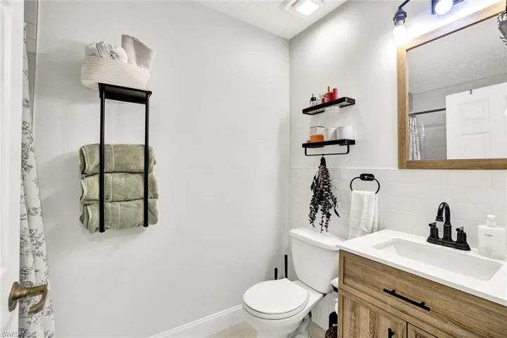 Full bath with curtained shower, vanity, a textured ceiling, and backsplash