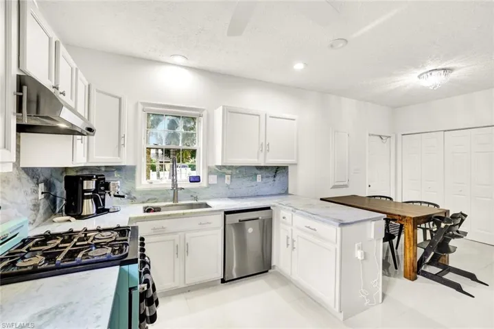 Kitchen featuring range with gas stovetop, white cabinetry, a peninsula, a ceiling fan, and a textured ceiling