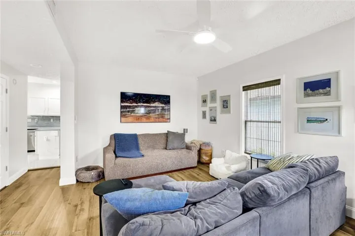 Living area with light wood-style flooring, a textured ceiling, and a ceiling fan