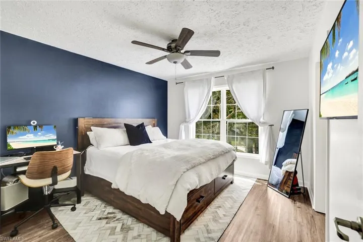Bedroom featuring wood finished floors, a textured ceiling, a ceiling fan, and an office area