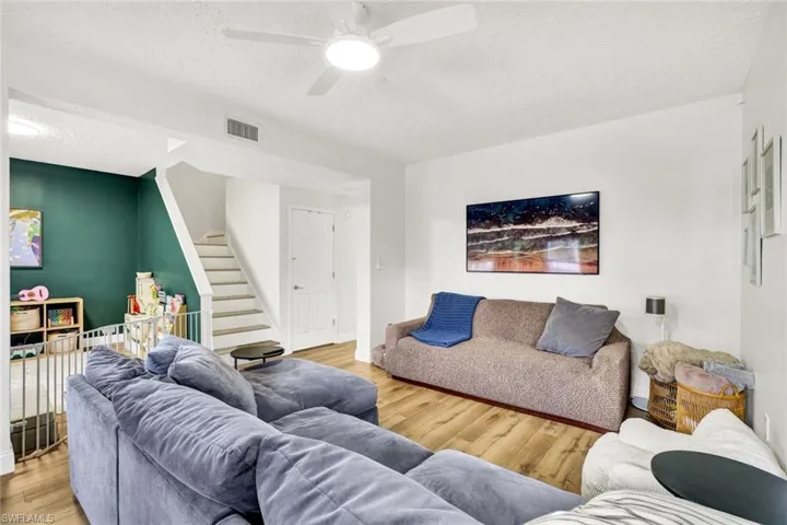 Living room with light wood-type flooring, a textured ceiling, and a ceiling fan