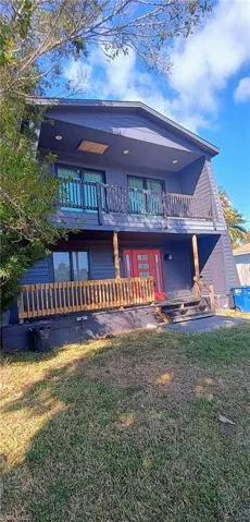 Back of property featuring a balcony and a lawn