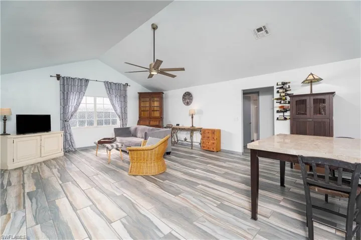 Living room featuring ceiling fan, light hardwood / wood-style floors, and vaulted ceiling