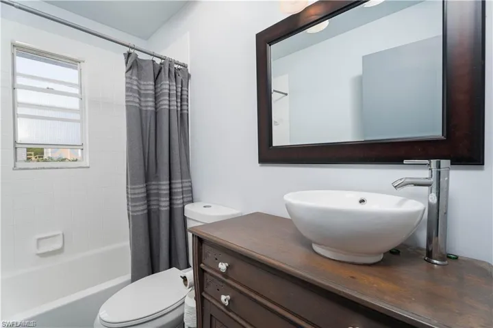 Full bathroom with vanity with extensive cabinet space, toilet, and shower / bath combo with shower curtain