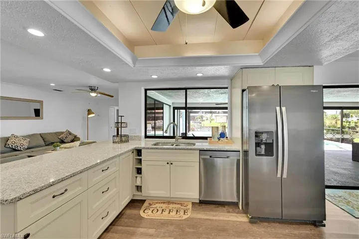 Kitchen featuring stainless steel appliances, a ceiling fan, light stone countertops, light wood-style floors, and recessed lighting
