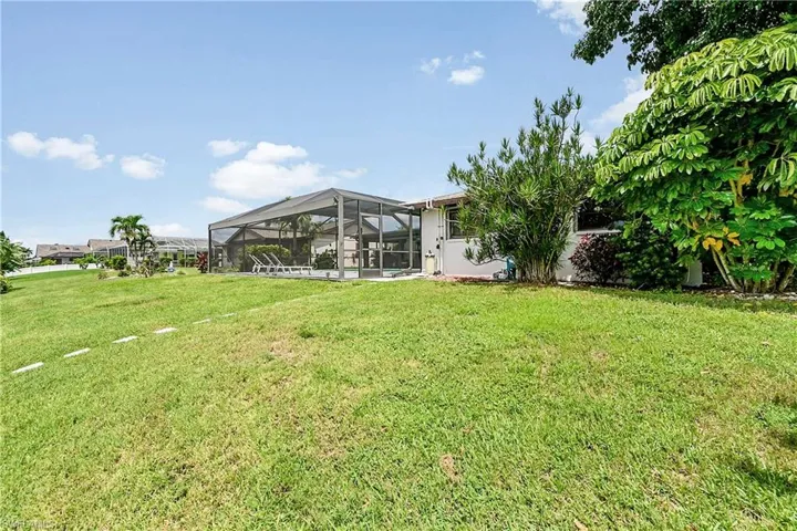 View of green lawn featuring a sunroom and glass enclosure