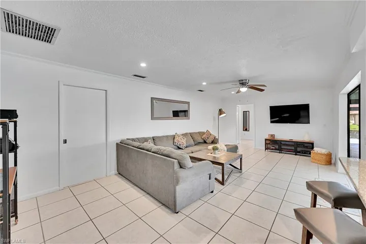 Living area featuring light tile patterned flooring, a textured ceiling, and ceiling fan