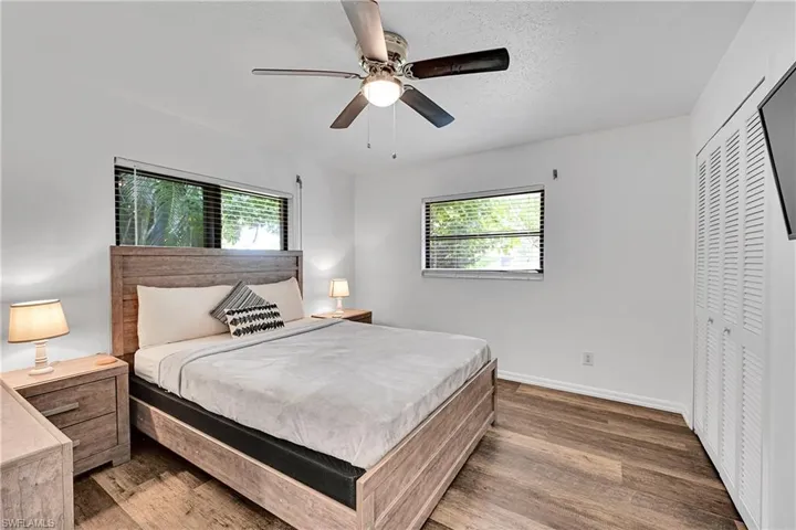 Bedroom featuring dark wood-style floors, multiple windows, a ceiling fan, a textured ceiling, and a closet