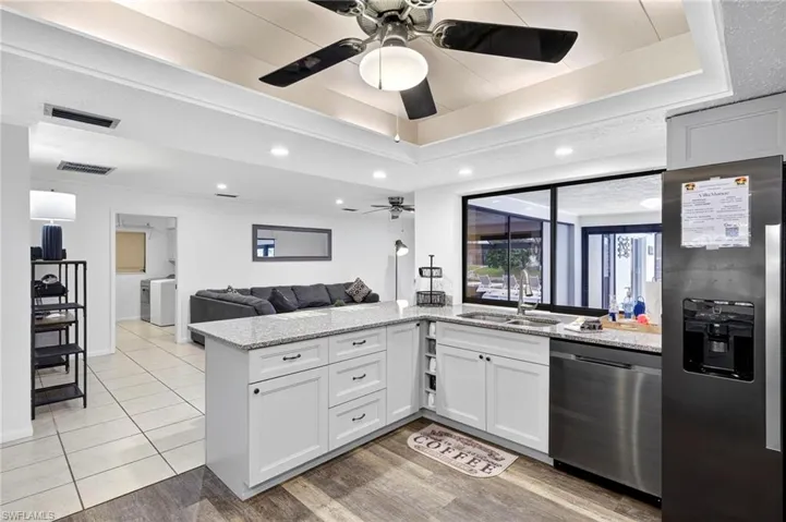 Kitchen featuring appliances with stainless steel finishes, light stone countertops, a peninsula, open floor plan, and a raised ceiling