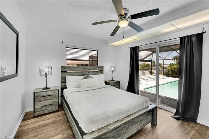 Bedroom with a textured ceiling, dark wood-style floors, access to outside, and a ceiling fan