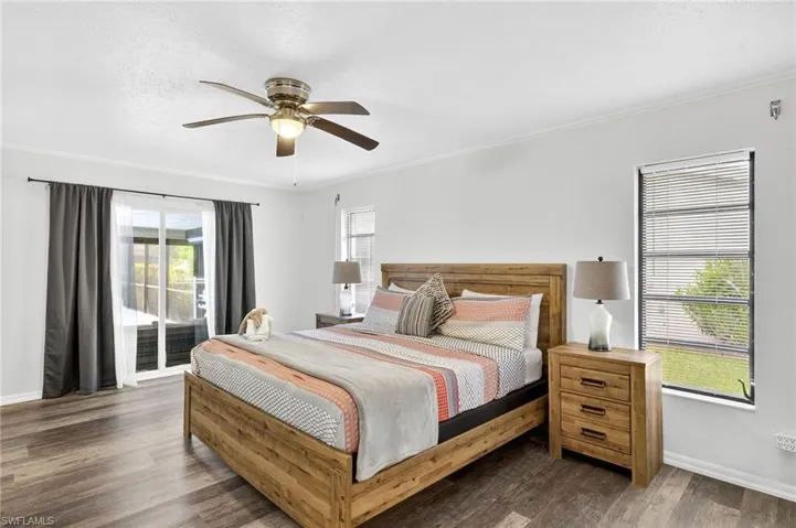 Bedroom featuring access to exterior, a textured ceiling, dark wood-type flooring, crown molding, and multiple windows