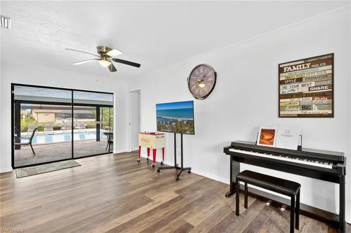 Living area featuring wood finished floors, crown molding, a ceiling fan, and a textured ceiling