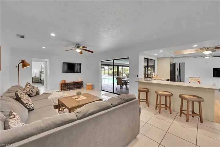 Living area featuring a ceiling fan, light tile patterned floors, recessed lighting, a textured ceiling, and a raised ceiling