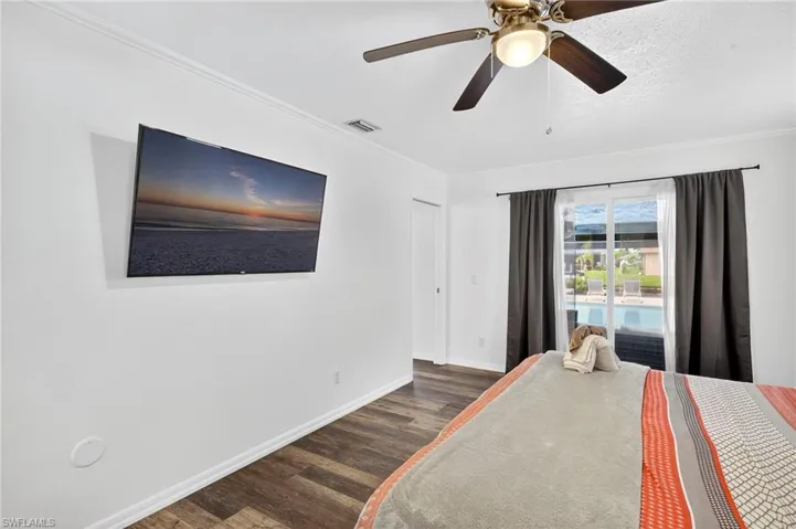 Bedroom featuring access to exterior, dark wood-type flooring, a ceiling fan, and crown molding